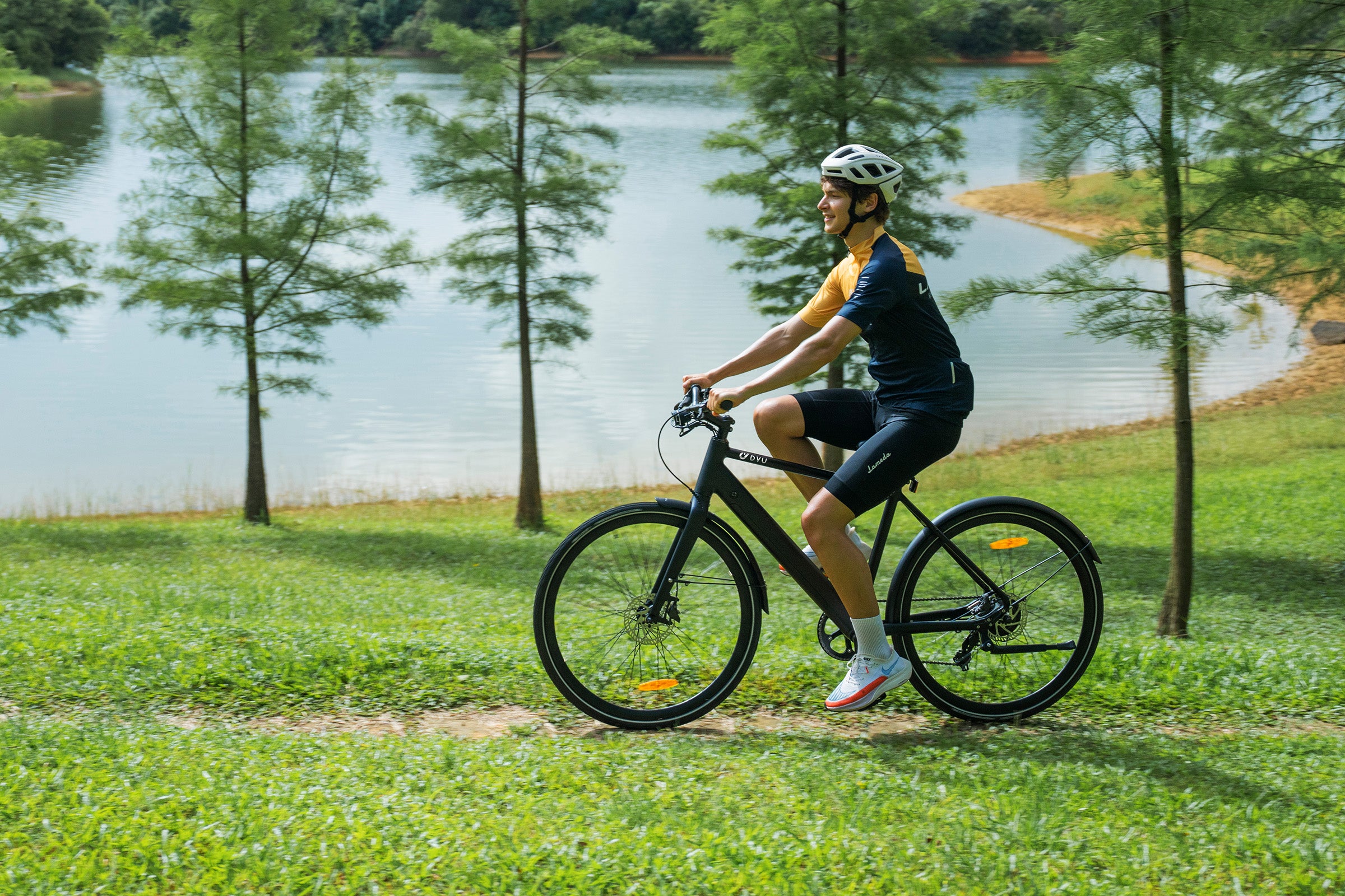 Rijder op DYU Stroll 1 elektrische fiets langs een tuin met bomen en een vijver. Rijder op DYU Stroll 1 elektrische fiets langs een tuin met bomen en een vijver.