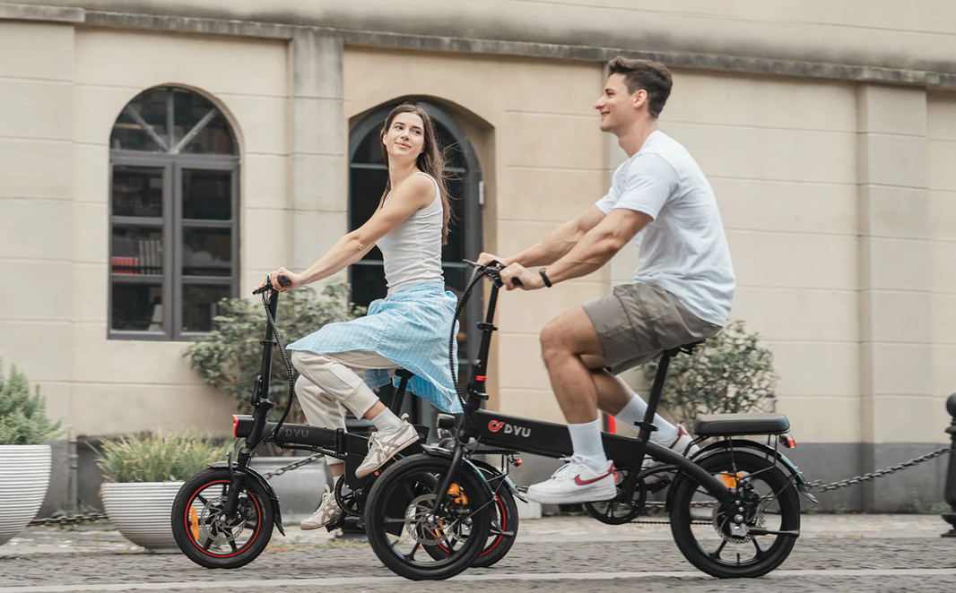 A man and a woman riding a black electric bicycle on the street