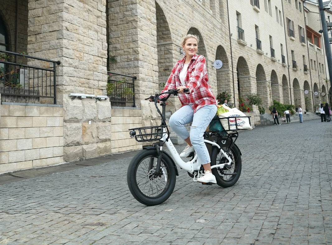 Vrouw rijdt op de DYU C9 vouwbare e-fiets over kasseien in een winkelstraat