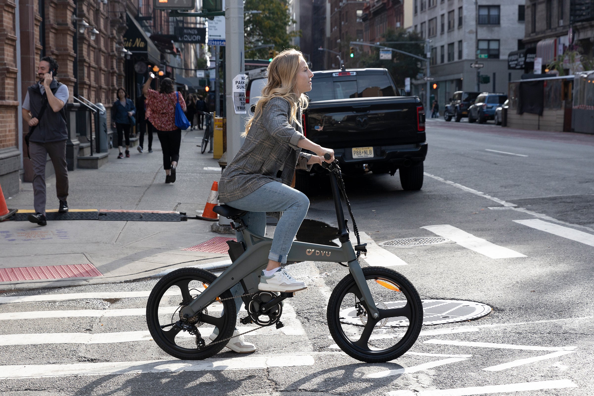 Vrouw rijdt op DYU elektrische fiets T1 over de straat, ideaal voor stedelijk vervoer.