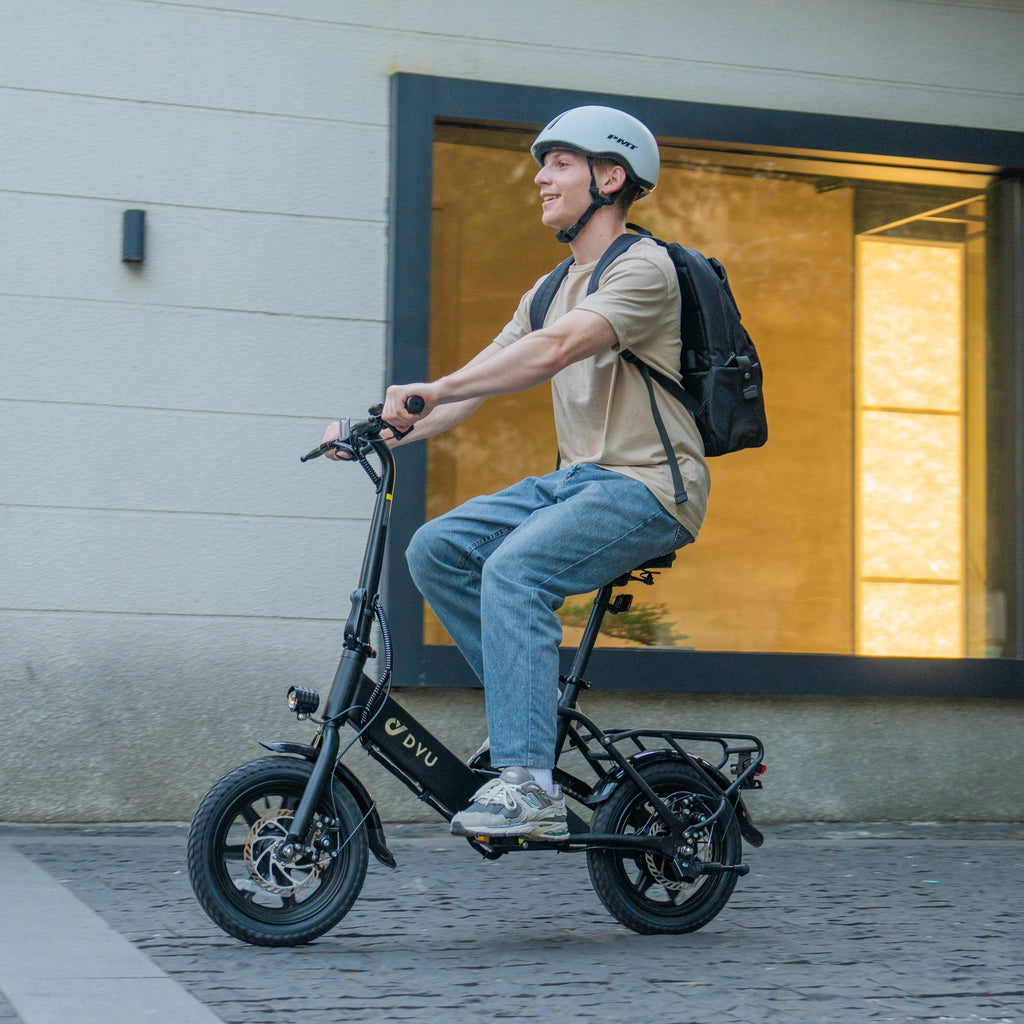 Man on DYU C3 14 inch zwarte vouw e-bike met rugzak en helm in de stad.